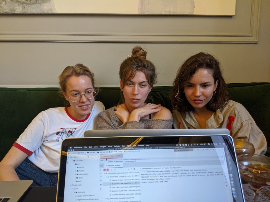 Three engineers sitting together in front of a laptop, watching an automated test run in the IDE console.