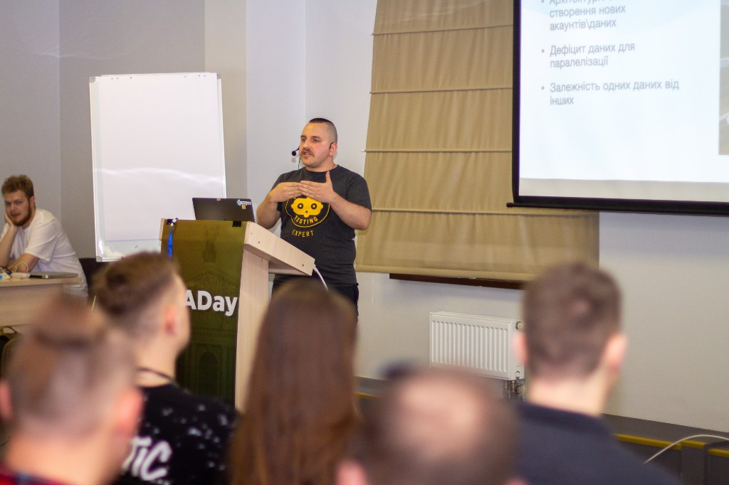 Oleksandr Khotemskyi speaking at a QA Day conference in front of a slide about test data problems.